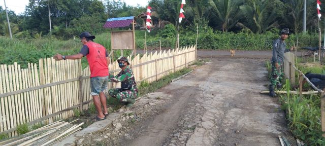 Personel TMMD ke 112 bantu mengecat pagar kantor desa